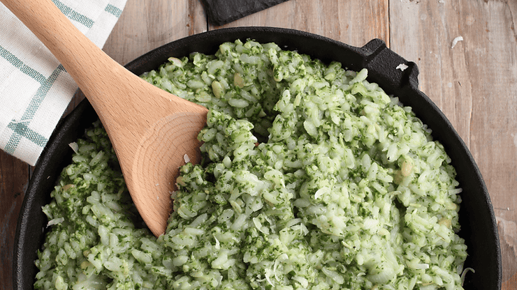 Creamy green risotto with pesto and a wooden spoon in a cast iron skillet, showcasing a low FODMAP meal option.