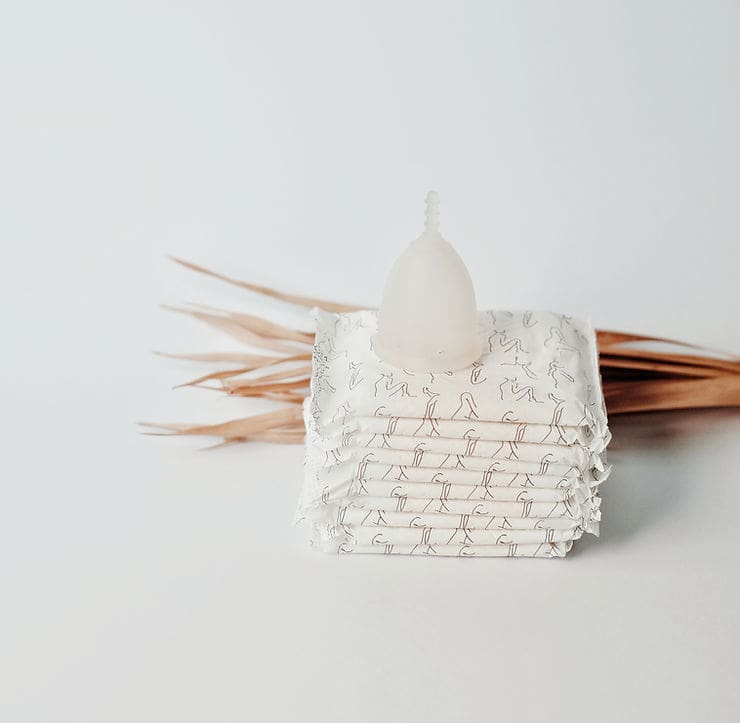 Menstrual products including pads and a menstrual cup, symbolizing hormonal changes and constipation before menstruation.